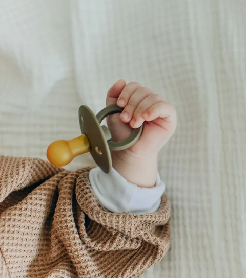 A baby's hand holding a pacifier
